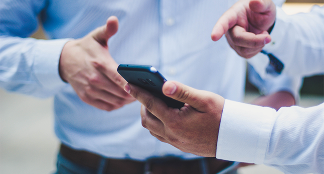 An image of two business people looking at a mobile phone