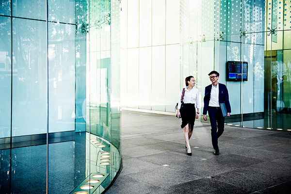 Two people walking past a modern office building